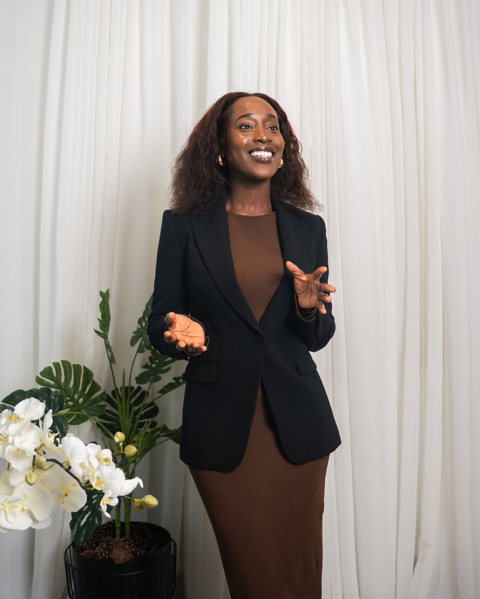 Steph smiling and speaking, standing in front of white curtains